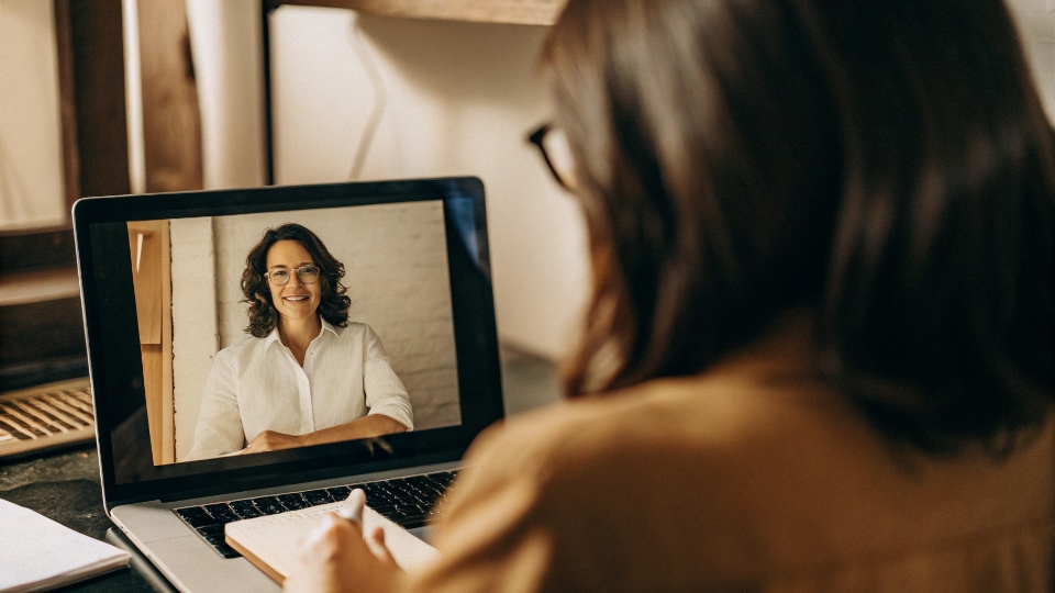 Dedicated Account Manager for Post-Shipment Support A friendly account manager on a video call, actively listening and taking notes to solve a client's problem.