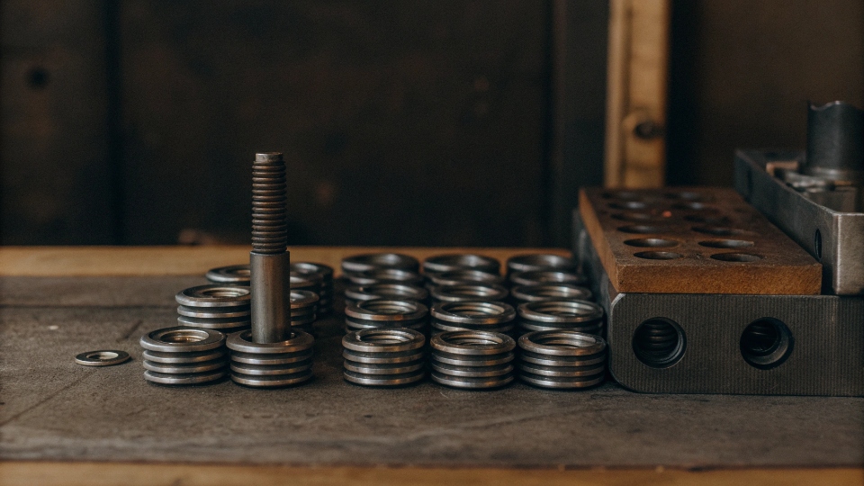 Lifespan of Custom Button Molds A steel mold for a jeans button shown next to a pile of finished buttons.