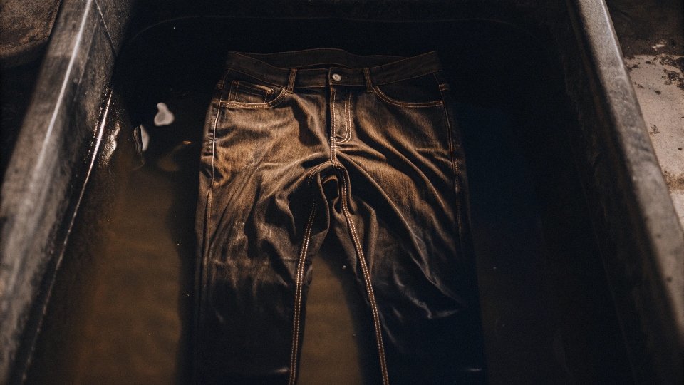 Soaking Jeans in a Vinegar Solution A pair of jeans submerged in a bathtub or a large bucket, illustrating a vinegar soak.