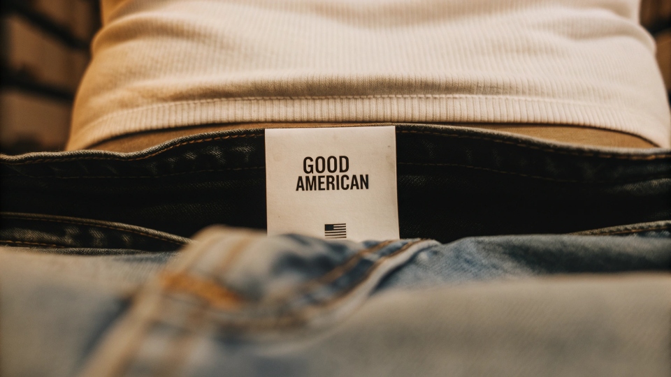 Brands Specializing in Curvy Jean Fits A close-up of the "Good American" brand label on a pair of jeans, symbolizing its focus on inclusive sizing.