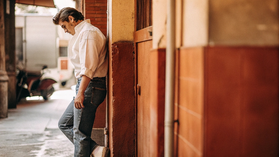 James Dean as a Denim Icon A classic black and white photo of James Dean in his iconic Lee 101 Riders jeans, leaning against a wall.