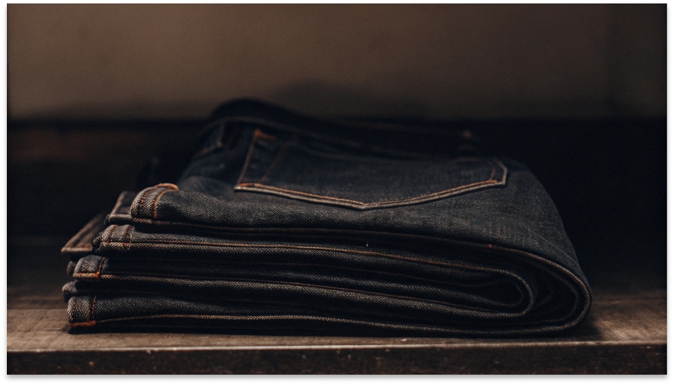 A Pair of 12 oz Midweight Jeans A folded pair of classic 12 oz blue jeans showing its texture and medium thickness.