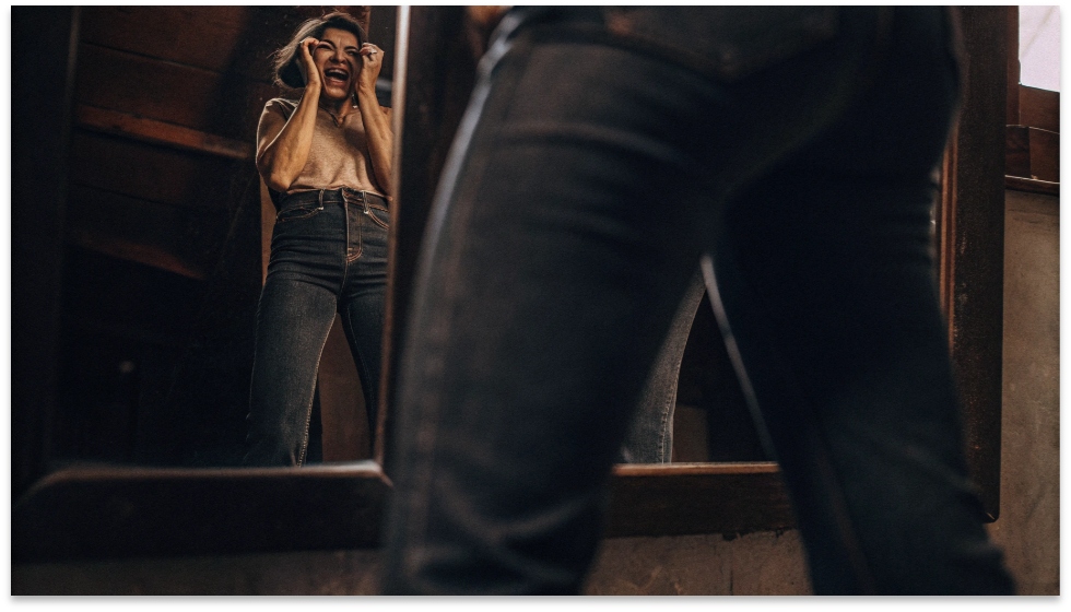 Frustration with Ill-fitting Straight-Leg Jeans A person looking in the mirror with a frustrated expression, wearing ill-fitting straight-leg jeans.