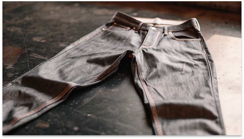 Flat Lay of Tapered Jeans A pair of dark wash tapered jeans laid flat, clearly showing how the leg narrows from the knee to the ankle opening.