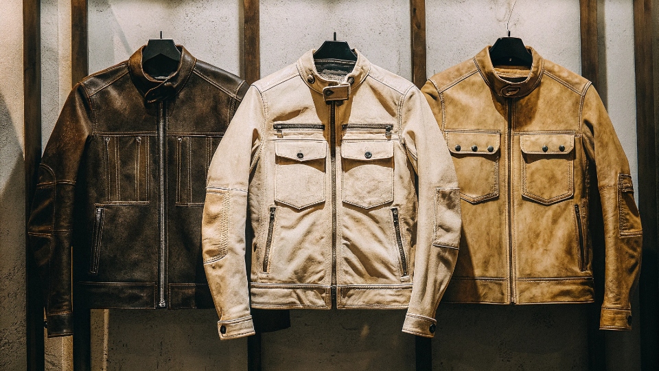 Best Types of Motorcycle Jackets A display of top-tier motorcycle jackets: a full leather jacket, a textile jacket, and a protective denim jacket, all showing CE armor inserts.