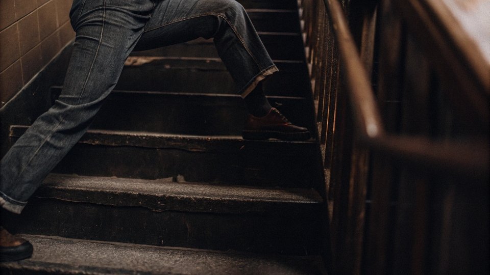 Breaking In Jeans with the Wear-Damp Method A person doing lunges or sitting on stairs in a pair of slightly damp jeans to create natural creases.
