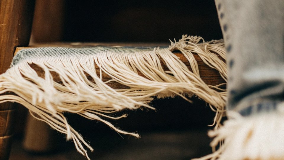 How to Fray Jean Hems A close-up shot of a perfectly frayed jean hem, showing the white weft threads.