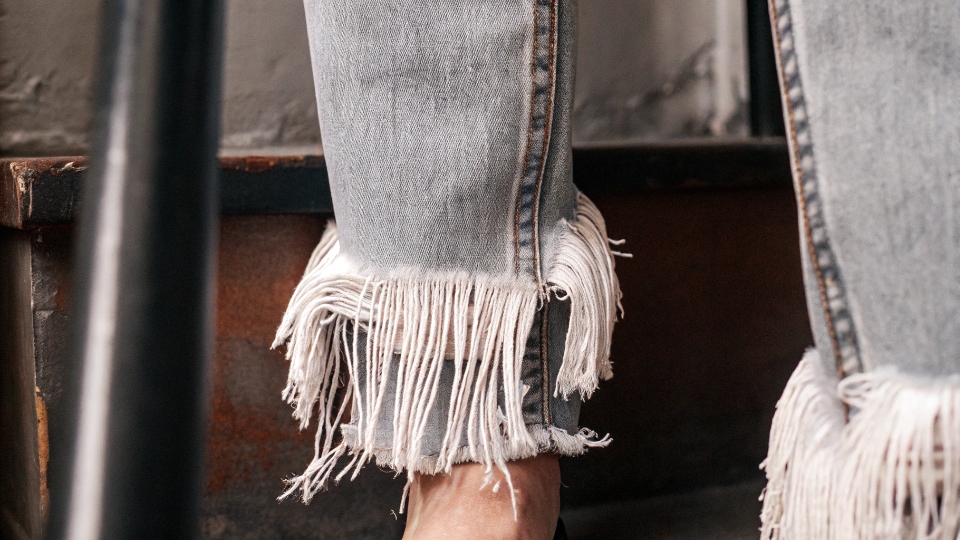 How to Fray Jean Hems A close-up shot of a perfectly frayed jean hem, showing the white weft threads.