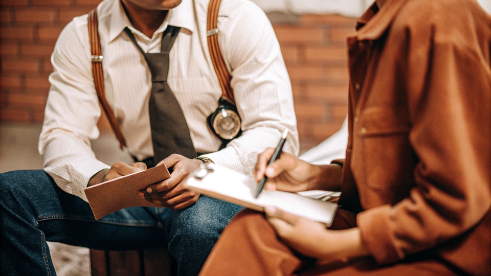 Detective in Jeans Conducting an Interview A police detective in dark jeans and a collared shirt interviewing a witness in a casual setting.