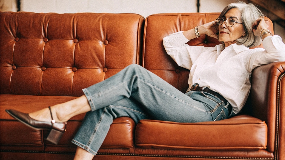 Ageless Style: Horseshoe Jeans for the Mature Woman A stylish 60-year-old woman with silver hair wearing horseshoe jeans and a crisp white shirt, looking elegant.