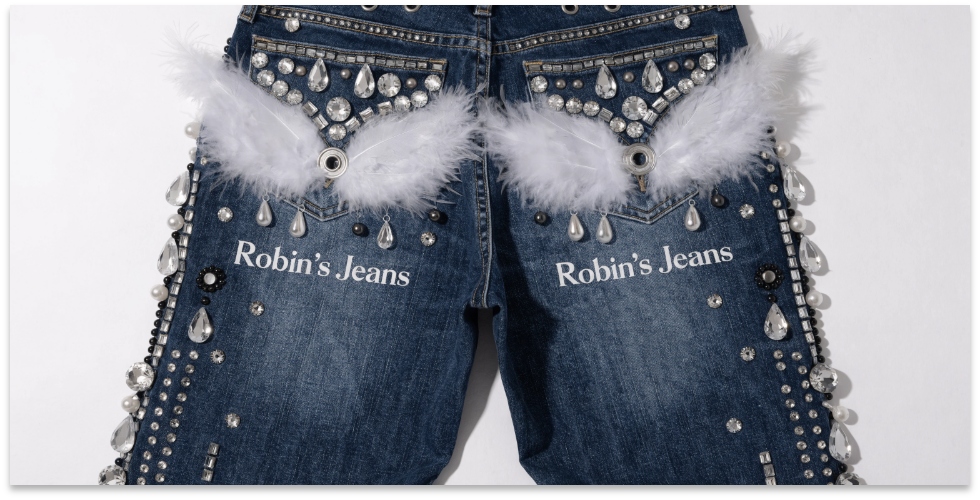 The Iconic Wings Logo of Robin's Jeans A pair of Robin's Jeans laid flat, focusing on the iconic angel wings logo on the back pockets.
