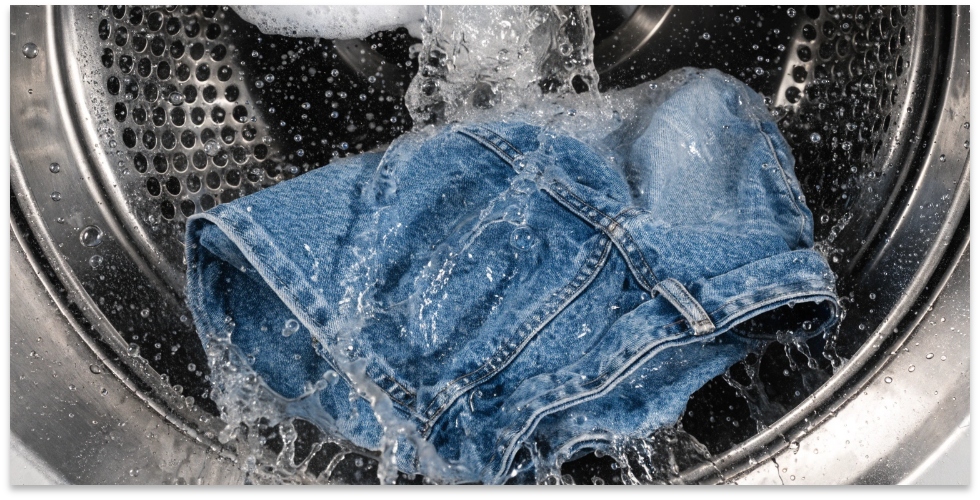 Washing Jeans Before Dyeing A pair of jeans tumbling alone in a washing machine, getting prepped for dyeing.