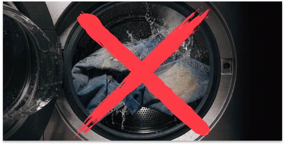 Do not wash jeans daily A large red X symbol placed over a washing machine filled with a single pair of jeans.